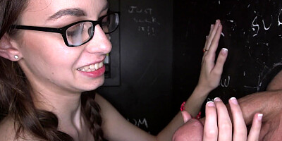 Girl with glasses is handling a cock in the glory hole naked