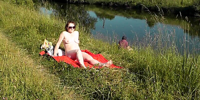 Naked mature woman is filmed while sunbathing by the river